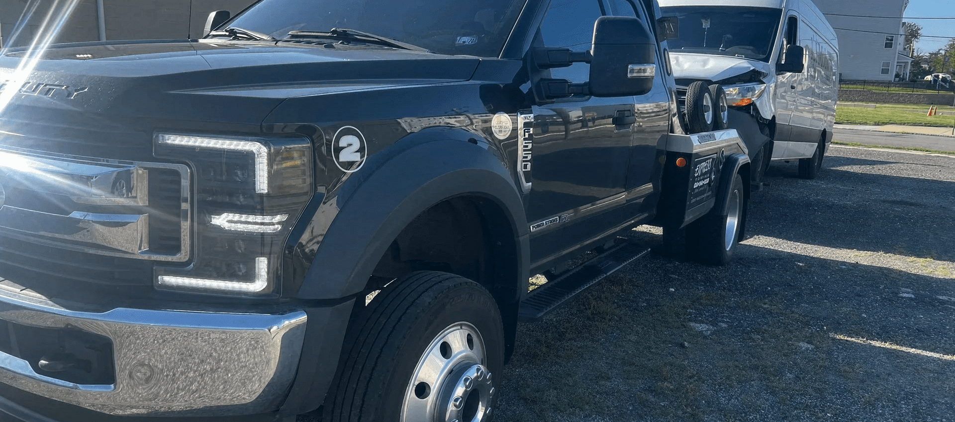 Black tow truck and van in sunlight